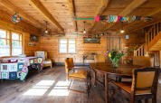 Intérieur de lodge rustique à Bełczna, murs en bois, décorations colorées, table ronde et chaises cuir.