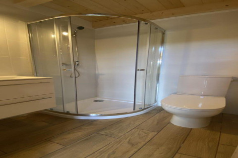 Modern badkamer met glazen douche en toilet in House by Lake Klępnica in Duitsland, houten vloer afwerking.