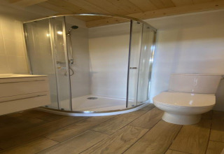 Moderne badkamer met glazen douchecabine en toilet bij House by Lake Klępnica in Duitsland, houten vloer.