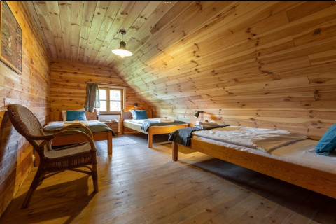 Gezellige kamer met drie eenpersoonsbedden en houten interieur in House by the road Skansen voor 10 personen, Bełczna.