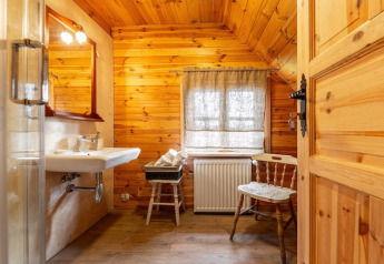 Badkamer met houten wanden, wastafel, stoel en raam in een knusse lodge in Bełczna, Duitsland