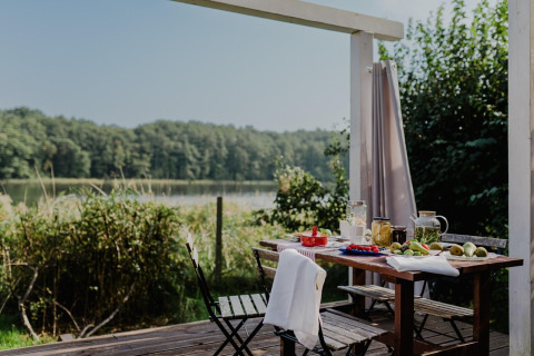 Buitentafel op terras bij House by Lake Klępnica in Duitsland met zicht op meer en bosrijke omgeving.