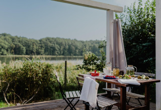 Udendørs bord på terrasse ved House by Lake Klępnica i Tyskland, med udsigt til sø og skov.