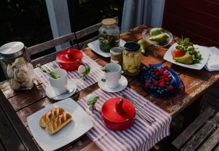 Udendørs morgenbord ved House by Lake Klępnica, Tyskland, med frugt, syltede grøntsager og bagværk.