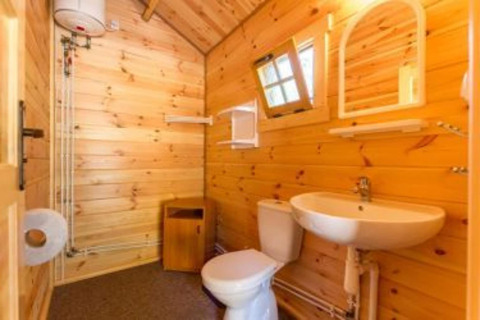Rustikt badeværelse i træ med vask, toilet og spejl i feriehytte 'Holiday cottages Łazy' i Danmark.