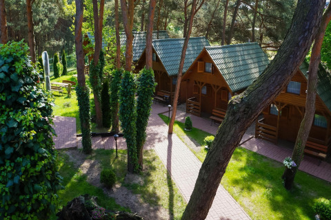 Houten vakantiewoningen met groene daken bij Holiday cottages Łazy in Denemarken, omringd door bomen.
