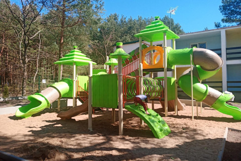 Kleurrijke speeltuin met glijbanen bij Holiday cottages Łazy, midden in een bosrijke omgeving.