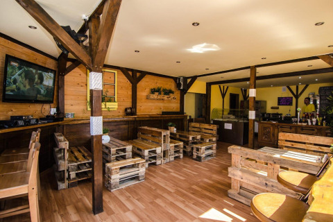 Wood-paneled lounge at Holiday cottages Łazy in Denmark, featuring rustic pallet furniture and a TV.