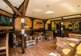 Træbeklædt lounge i Holiday cottages Łazy, Danmark, med pallerustikke møbler og afslappet atmosfære.