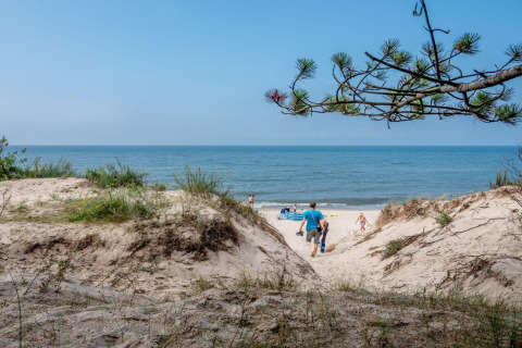 Familier går gennem klitterne mod stranden ved Holiday cottages Łazy på en solrig dag ved havet.