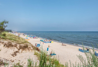 Playa de arena con dunas y personas disfrutando cerca del mar junto a Holiday cottages Łazy en Dinamarca.