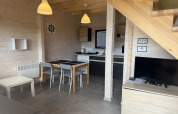Salon et cuisine modernes dans un cottage de vacances à deux étages à Mielenko, avec table et télévision.