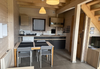 Intérieur d’un cottage de vacances à deux étages avec cuisine moderne, table à manger et escalier en bois.