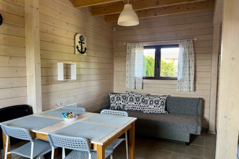 Hyggelig stue i to-etagers feriehus i Mielenko, Danmark, med spisebord og sofa ved vinduet.