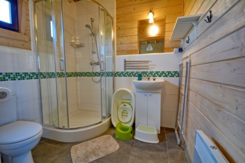Moderne badkamer in houten lodge met douche, lavabo, toilet en kinderaccessoires in Mielenko.