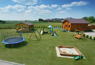 Stor græsplæne ved feriehus i Mielenko med legeplads, sandkasse, gynger, rutsjebane og trampolin.