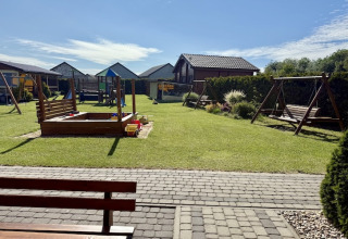 Speelruimte bij tweeverdiepingsvakantiehuisjes voor maximaal 6 personen in Mielenko, Denemarken, met schommels en zandbak.