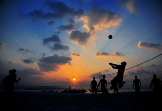 Folk spiller beachvolleyball ved solnedgang på stranden ved Two-storey holiday cottages i Mielenko, Danmark.