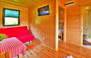 Houten zomerhuisinterieur met rode zetel, tv en eettafel in Mielno, Denemarken voor vijf personen.