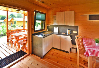 Knus zomerhuisje in Mielno voor 5 personen, met keuken, eettafel en houten terras met zitje buiten.