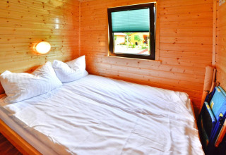 Slaapkamer in een zomerhuisje met tweepersoonsbed, houten wanden en raam voor 5 personen in Mielno.