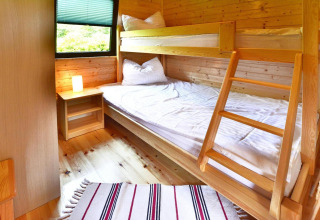 Gezellige houten slaapkamer met stapelbed, nachtkastje en raam in zomerhuisjes in Mielno, Denemarken.
