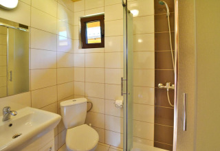 Lichte moderne badkamer in zomerhuisje voor 5 personen Mielno met douche, toilet, wastafel en raam.