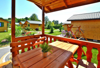 Uitzicht vanaf de veranda van een zomerhuisje in Mielno, Denemarken met houten meubelen en tuin.