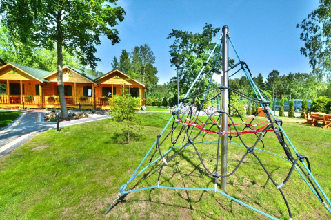 Buitenaanzicht van zomerhuisjes voor 5 personen in Mielno met speeltuin en groene omgeving.