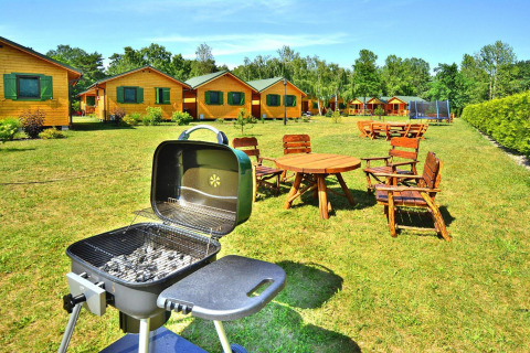 Sommerhäuser für 5 Personen in Mielno mit Grill und rustikalen Holzmöbeln im sonnigen Außenbereich.