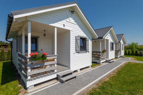 Witte vakantiehuisjes bij Holiday cottages in Gąski, met bloemen aan de veranda’s en tuin.