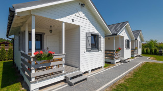 Photo of white holiday cottages at Holiday cottages in Gąski, featuring porches with flowers.