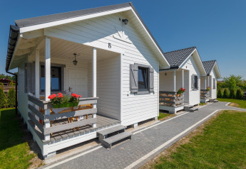 Feriefoto af hvide sommerhytter ved Holiday cottages i Gąski, med blomster og grøn have.