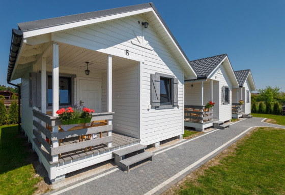 Witte vakantiehuisjes bij Holiday cottages in Gąski, met bloemen aan de veranda’s en tuin.