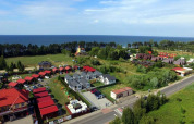 Vakantiehuisjes in Gąski aan zee, omringd door natuur en groen, luchtopname op een heldere dag.