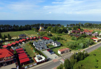Cottages de vacances à Gąski près de la mer, entourés de verdure, vue aérienne lors d'une journée ensoleillée.
