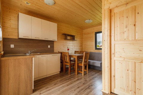Binnenzicht van een vakantiehuisje in Gąski met houten keuken, eetruimte, tafel en stoelen.
