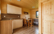 Interior de una cabaña vacacional en Gąski con cocina moderna, paredes de madera y comedor luminoso.