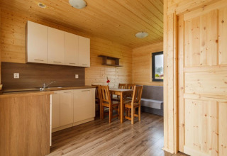 Binnenzicht van een vakantiehuisje in Gąski met houten keuken, eetruimte, tafel en stoelen.