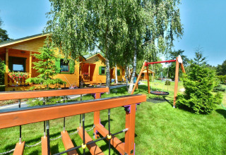 Sommerhäuser für 5 Personen in Mielno, umgeben von grüner Natur, Spielplatz und hellem Himmel.