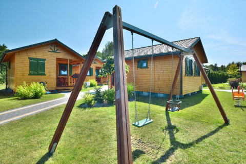 Sommerhäuser für 5 Personen in Mielno, Dänemark. Holzspielplatz und grüne Wiese vor Blockhütten.