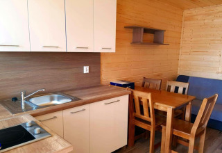 Modern kitchen and dining area in a holiday cottage in Gąski, Denmark, featuring wooden furniture and walls.