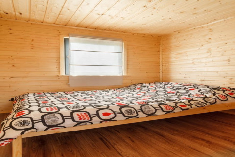 Slaapkamer met houten afwerking in 'Holiday cottages in Gąski' in Denemarken, met bed en raam.