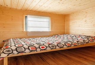 Slaapkamer met houten afwerking in 'Holiday cottages in Gąski' in Denemarken, met bed en raam.