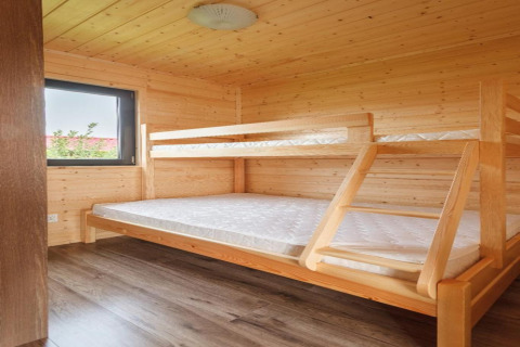 Houten chaletkamer met stapelbed en raam, interieur van Holiday cottages in Gąski, Denemarken.