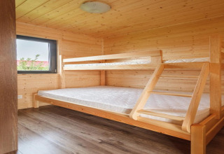 Houten chaletkamer met stapelbed en raam, interieur van Holiday cottages in Gąski, Denemarken.