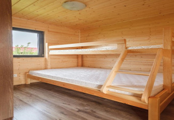 Dormitorio de cabaña de madera con literas y ventana en Holiday cottages in Gąski, estilo sencillo.