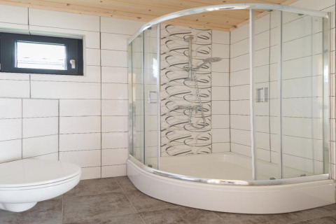 Moderne badkamer met gebogen glazen douche, wandtoilet en raam, Holiday cottages in Gąski, Denemarken.