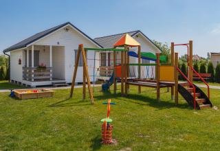 Speeltuin met kleurrijke toestellen bij de witte vakantiehuisjes van Holiday cottages in Gąski, Denemarken.