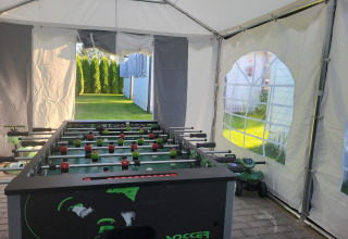 Voetbaltafel in een tent met zicht op de tuin aan de vakantiewoningen in Gąski, Denemarken.